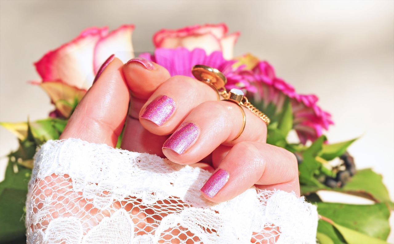 main manucurée devant bouquet de fleurs rose